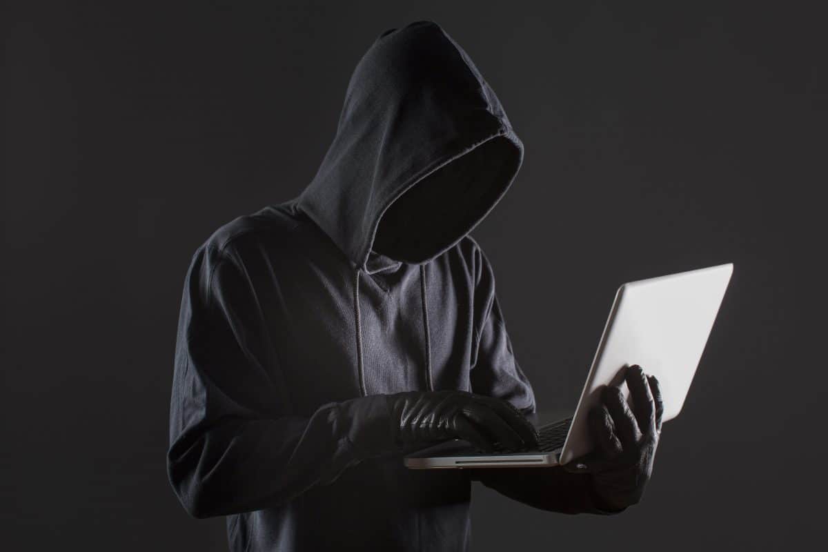 image of an anonymous hacker holding a laptop